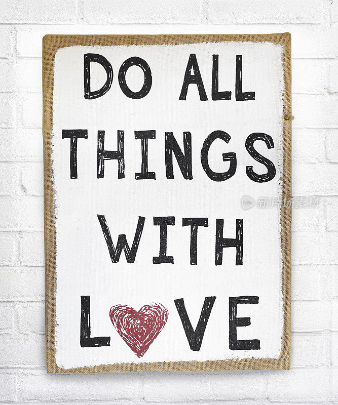 Quote do everything with love text on hanging sign board against white砖墙